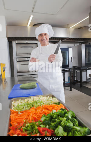 Lo chef sorridente holding coltello da cucina da verdure crude Foto Stock