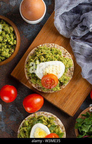 Avocado con uovo e pomodoro su torte di riso Foto Stock