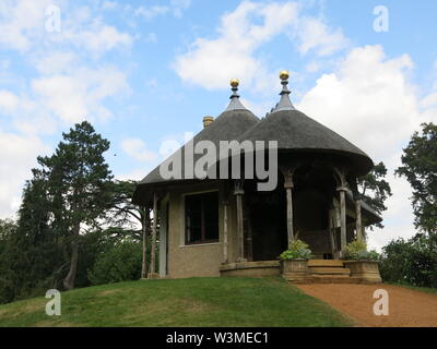 Il round cottage con il tetto di paglia su una collinetta artificiale presso lo Swiss Garden a Shuttleworth, un paesaggio regency giardino creato in stile pittoresco. Foto Stock