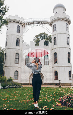 Donna che mantiene ombrello rosso da Schloss Pfaueninsel a Potsdam, Germania Foto Stock