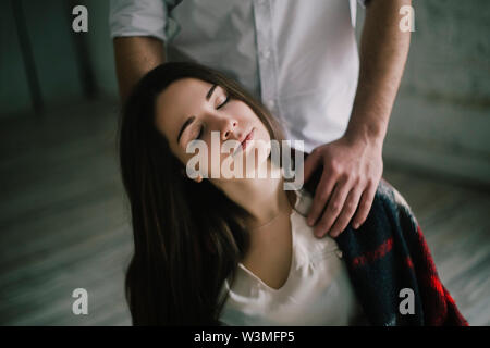 Donna con gli occhi chiusi e mani dell'uomo sulle sue spalle Foto Stock