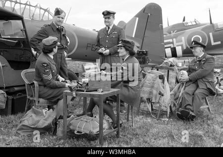 Battaglia della Gran Bretagna era la seconda guerra mondiale lo scenario con i piloti, WRAFs & equipaggio a terra engineer re-enactors in discussione. Piani. Monocromatico. Bianco & nero Foto Stock