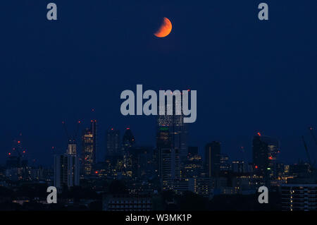 La luna piena "Buck Moon" che sorge su Londra. Un'eclissi lunare parziale vista da Parliament Hill a Hampstead Heath, Londra, Inghilterra, Regno Unito, Regno Unito Foto Stock