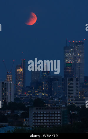 La luna piena "Buck Moon" che sorge su Londra. Un'eclissi lunare parziale vista da Parliament Hill a Hampstead Heath, Londra, Inghilterra, Regno Unito, Regno Unito Foto Stock