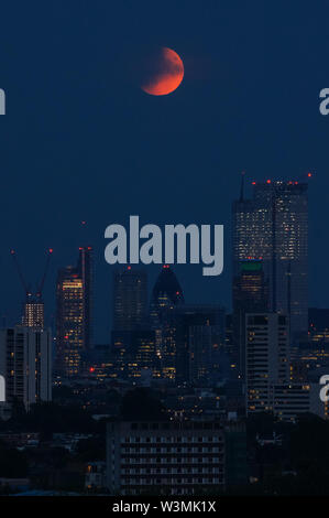 La luna piena "Buck Moon" che sorge su Londra. Un'eclissi lunare parziale vista da Parliament Hill a Hampstead Heath, Londra, Inghilterra, Regno Unito, Regno Unito Foto Stock