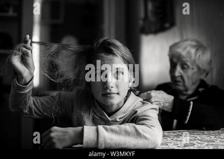 Nonnina, vecchia donna trecce il suo pronipote di capelli. La fotografia in bianco e nero. Foto Stock