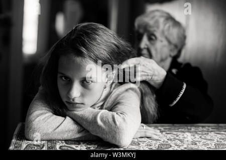 Una vecchia donna trecce il suo pronipote di capelli. La fotografia in bianco e nero. Foto Stock