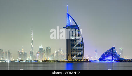 Splendida vista dell'illuminato skyline di Dubai durante il tramonto con il magnifico Burj Khalifa in background e un hotel di lusso in primo piano. Foto Stock