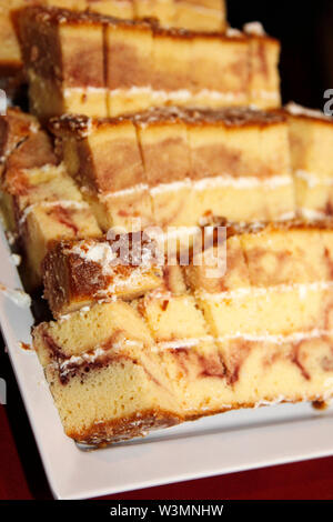 Sfornato fresco marmo torta tagliata in dimensioni del dito pezzi con la ciliegina su un piatto di portata Foto Stock