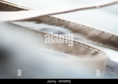 Il beige sottile nastro di trasporto curvo realizzato in vera pelle con un filato di cucitura, close-up per lo sfondo, il fuoco selettivo Foto Stock