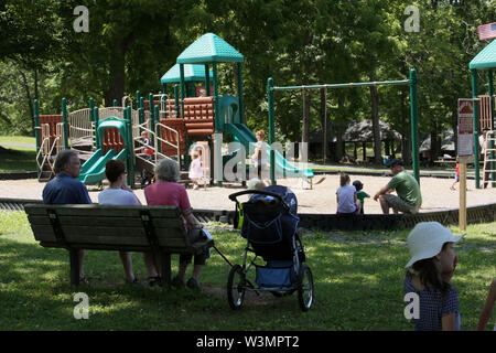 I genitori supervisionare i bambini al parco giochi Foto Stock