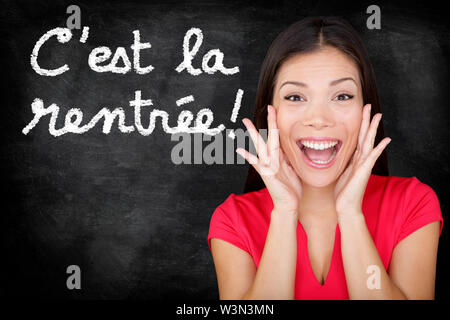 Cest la Rentree Scolaire - studente francese urlando felice torna a scuola scritto in francese sulla lavagna dall insegnante di donna. Sorridendo felice femmina di insegnamento in lingua francese o college universitario studente Foto Stock