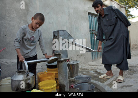 Hakim, 11, raccoglie l'acqua potabile da un pubblico la pompa a mano, l'unica fonte di acqua potabile nel suo quartiere a Kabul, la capitale. Altri bambini, circondata da secchi e taniche, attendere il loro turno. Egli vende anche i sacchetti di plastica al mercato e aiuta la sua madre cucire i pulsanti sulla sicurezza di protezione uniformi, una fiorente industria di nicchia. Hakim non frequentano scuole regolari, ma tiene corsi di formazione di base, così come la pittura e judo a Aschiana, una ONG locale che serve i bambini che vivono o lavorano nelle strade. L'Afghanistan. Luglio 12, 2007. Foto Stock