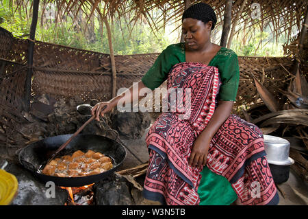 Mtumono Juma, 30 anni donna fare ciambelle locali presso la cucina del suo ristorante sul ciglio della strada. Lei non è sposata e supporta i suoi genitori con profitto dalla sua azienda. Mbuzini villaggio nella zona Chuni di Zanzibar, Tanzania. Dicembre 24, 2008. Foto Stock