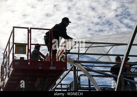 Greymouth, Nuova Zelanda, dicembre 12, 2018: Commercianti fissare la plastica su un nuovo tunnel house. Foto Stock