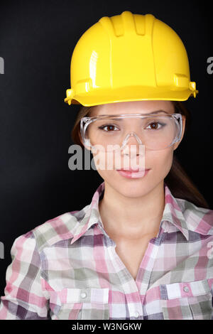 Operaio edile w gli occhiali di sicurezza e di compressori hardhat ritratto su sfondo nero. Foto Stock