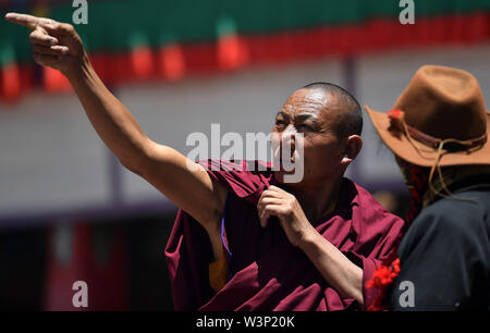 Xigaze, la Cina della regione autonoma del Tibet. 16 Luglio, 2019. Un monaco introduce Thangka dipinti durante un thangka dispiegarsi cerimonia presso un monastero della setta Gelug del buddhismo tibetano in Xaitongmoin contea di Xigaze, a sud-ovest della Cina di regione autonoma del Tibet, 16 luglio 2019. Credito: Chogo/Xinhua/Alamy Live News Foto Stock