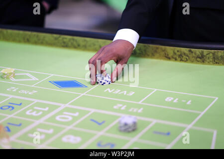 Mano croupier con chip sul tavolo da gioco del casinò Foto Stock