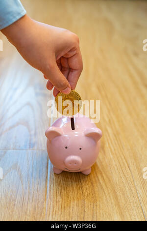 Stretta di mano umana inserendo golden bitcoin in piggybank Foto Stock