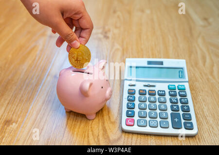 Donna mano azienda golden bitcoin messo in salvadanaio Foto Stock
