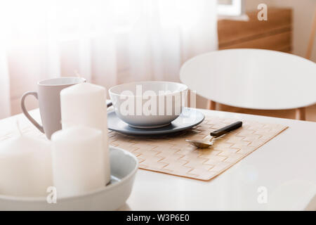 Posate, tazze e la piastra e le candele per la decorazione sono sul tavolo della cucina. Foto Stock
