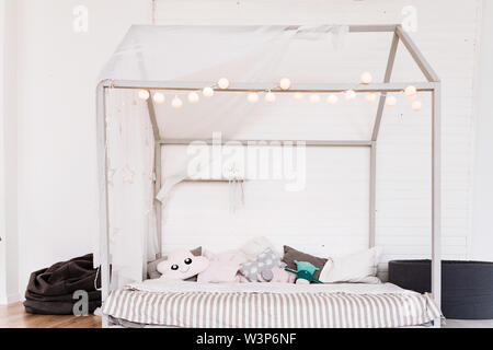 Spaziosa camera da letto della bambina. Pavimento in legno con tappeti,  culla di bianco e decorazioni colorate Foto stock - Alamy