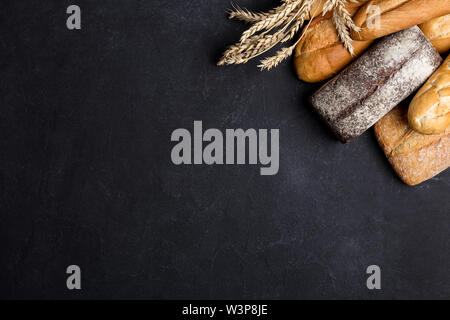 Vari tipi di pane sulla tavola nera. vista superiore, piana, laici copia spazio per il testo Foto Stock