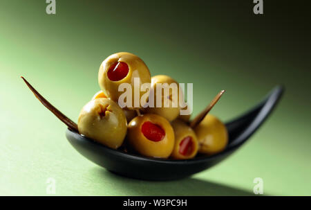 Stuzzicanti Olive farcite con peperoncino rosso in nero piccolo recipiente. Foto Stock