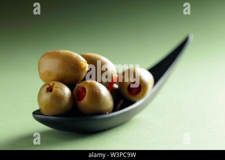 Stuzzicanti Olive farcite con peperoncino rosso in nero piccolo recipiente. Foto Stock