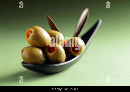 Stuzzicanti Olive farcite con peperoncino rosso in nero piccolo recipiente. Foto Stock