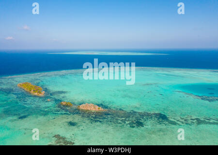 Atoll e mare blu, vista da sopra. Seascape da giorno. Il turchese e il blu del mare di acqua. Le piccole isole coralline. Foto Stock