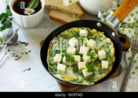 La colazione dello sfondo. Uova fritte con spinaci, formaggio feta sul tavolo di pietra. Spazio libero per il tuo testo. Foto Stock