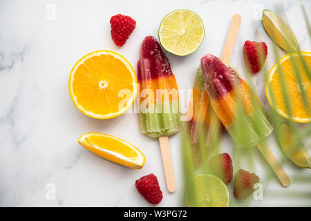 Estate ghiaccioli con frutta e un tropicale di foglie di palma Foto Stock