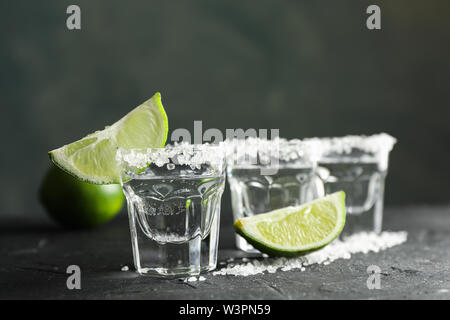 Scatti di Tequila con sale e fettine di lime su sfondo nero Foto Stock