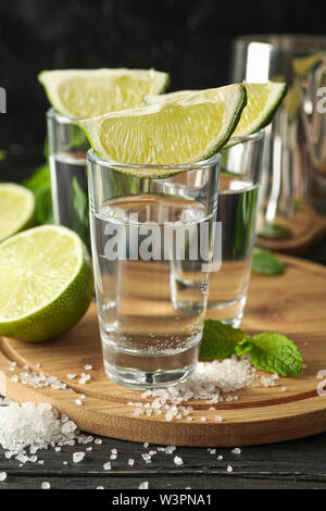 Tequila scatti con fettine di lime, sale e menta su sfondo di legno Foto Stock