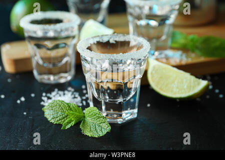 Scatti di Tequila con sale, fettine di lime e menta sulla tavola nera Foto Stock