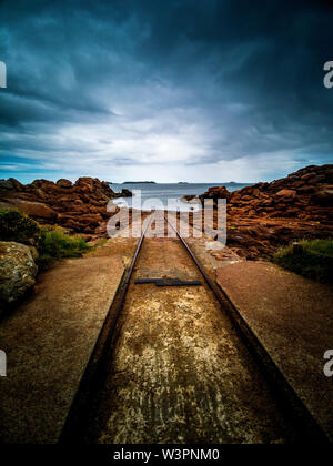 Le vie conducono giù al mare presso la stazione di salvataggio al francese Breton porto di pesca di Ploumanach. Bretagne. Francia Foto Stock