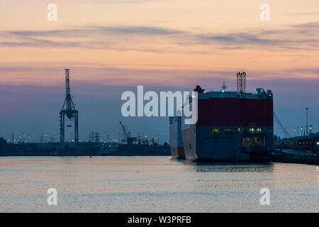 Le navi da carico a Southampton docks al tramonto su una serata estiva, Hampshire, Regno Unito Foto Stock