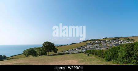 Birra, Seaton, Devon, Inghilterra, Regno Unito. Caravan Park di birra a testa alta e di terra che si affaccia sul mare con un cielo blu chiaro. Foto Stock