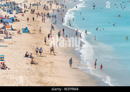 I villeggianti rilassante, dove poter prendere il sole e nuotare nel mare turchese a Fistral a Newquay in Cornovaglia. Foto Stock