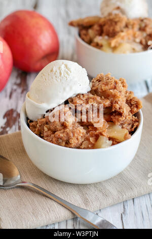 Fresche fatte in casa a caldo apple crisp o crumble con croccante di streusel topping e rabboccato con baccelli di vaniglia gelato. Messa a fuoco selettiva con sfondo sfocato. Foto Stock