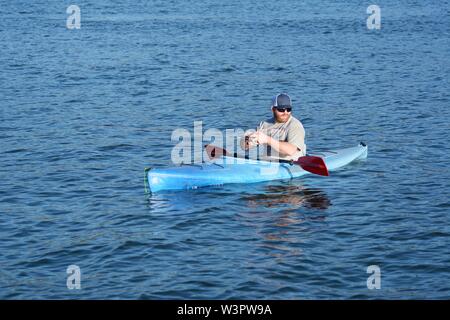 Un vero pescatore felice con catturato piccoli bassi sul suo colore blu kayak sul lago chiara Clearlake California USA America sulla tranquilla giornata di sole in estate da se stesso Foto Stock