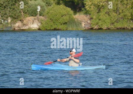 Un vero pescatore felice con catturato piccoli bassi sul suo colore blu kayak sul lago chiara Clearlake California USA America sulla tranquilla giornata di sole in estate da se stesso Foto Stock