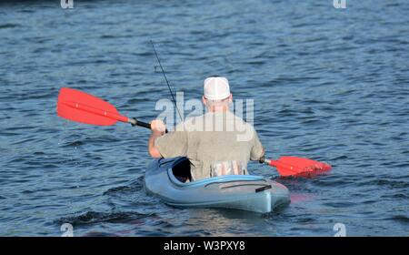 Un vero pescatore felice con catturato piccoli bassi sul suo colore blu kayak sul lago chiara Clearlake California USA America sulla tranquilla giornata di sole in estate da se stesso Foto Stock