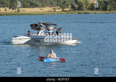 Un vero pescatore felice con catturato piccoli bassi sul suo colore blu kayak sul lago chiara Clearlake California USA America sulla tranquilla giornata di sole in estate da se stesso Foto Stock