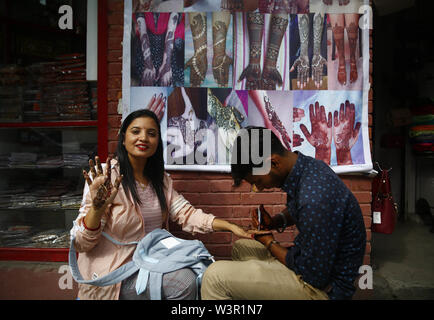 Kathmandu, Nepal. 17 Luglio, 2019. Una donna mostra il suo decorate a mano con henna sulla Shravan, un mese quando le donne culto Signore Shiva, lungo una strada a nuova strada a Kathmandu, Nepal Mercoledì, 17 luglio 2019. In questo mese le donne e le ragazze e mantenere veloce e adornano verde. Le ragazze nubili mantenere veloce su lunedì al desiderio di ottenere il marito di sua scelta mentre le donne sposate tenere il veloce per la buona salute dei loro mariti e i membri della famiglia. Credito: Skanda Gautam/ZUMA filo/Alamy Live News Foto Stock