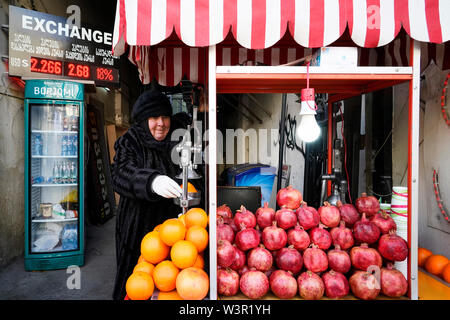 Una commessa locale è la vendita di succo di arancia e il succo di melograno per le strade di Tbilisi. Dzveli Tbilisi Tbilisi, Georgia, Caucasia, Eurasia Foto Stock