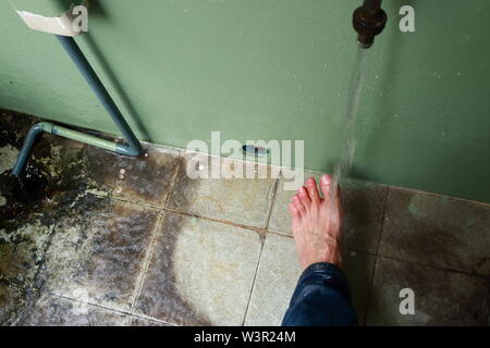 Movimento sfocate di acqua che scorre sul piede sinistro e le dita dei piedi di un uomo asiatico Foto Stock