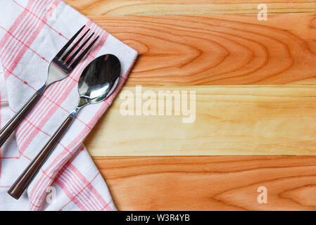 Tovaglia a scacchi red andwhite con cucchiaio e forchetta sul tavolo da pranzo in legno / napery Foto Stock