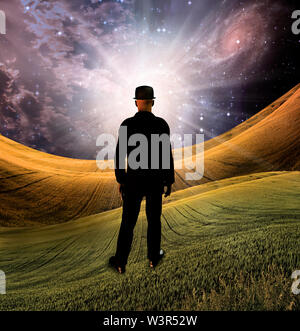 Esplosione di fantasia. Uomo in abito nero sta davanti a una luce brillante nel paesaggio surreale Foto Stock